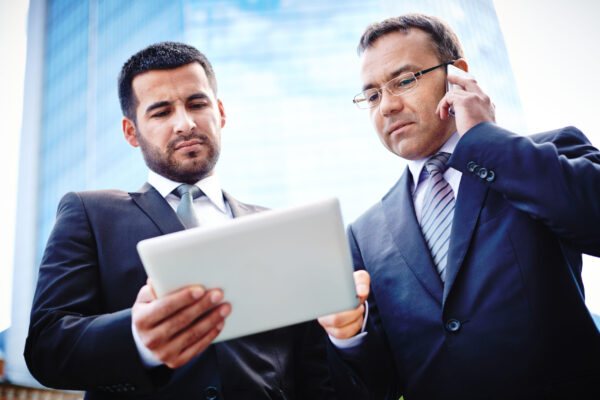 Experienced businessmen discussing details of the project and negotiating with their client on the phone